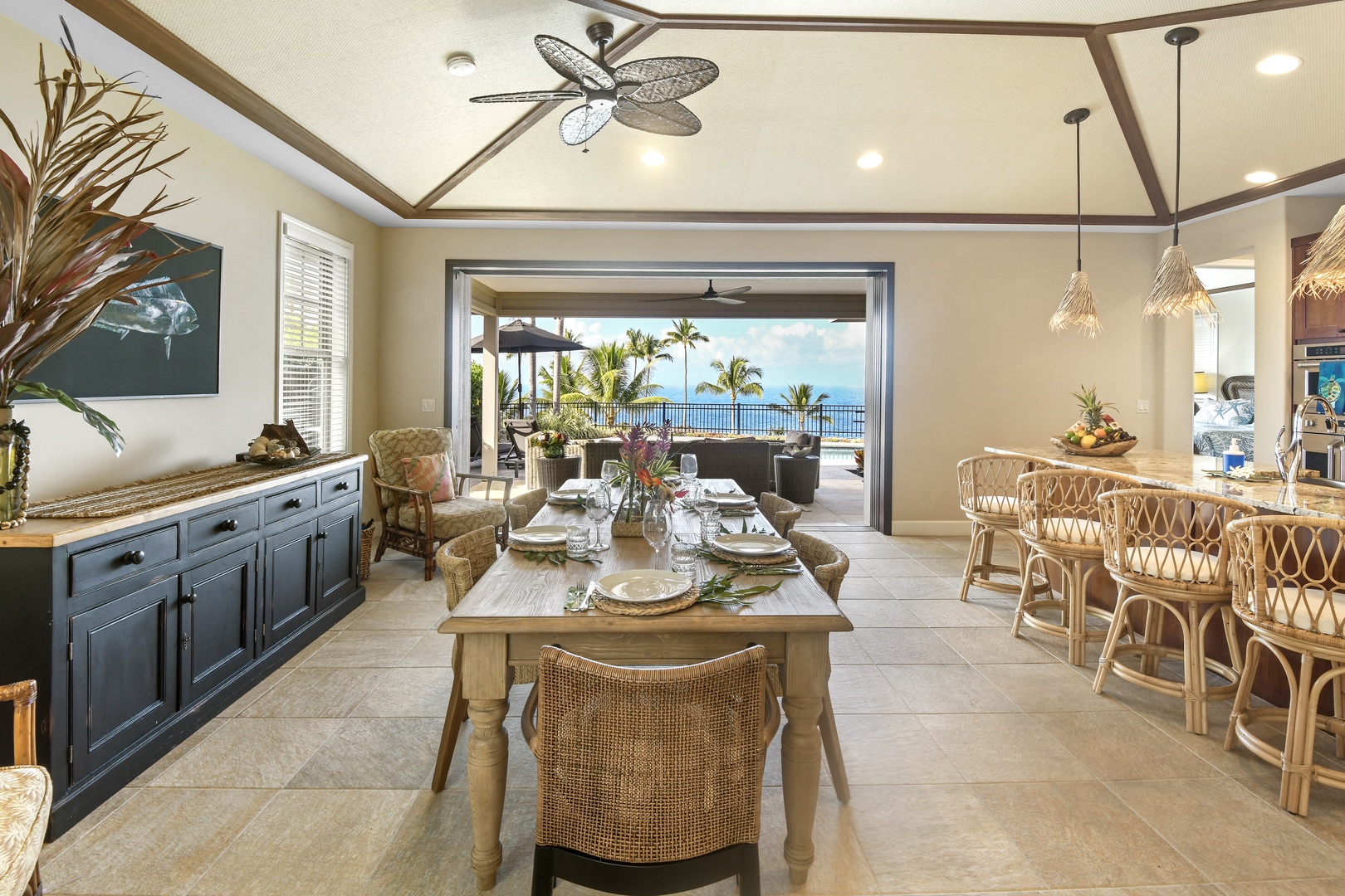 Unwind in your tropical open-concept living space where ocean breezes flow freely through expansive doors, creating the perfect indoor-outdoor dining experience.