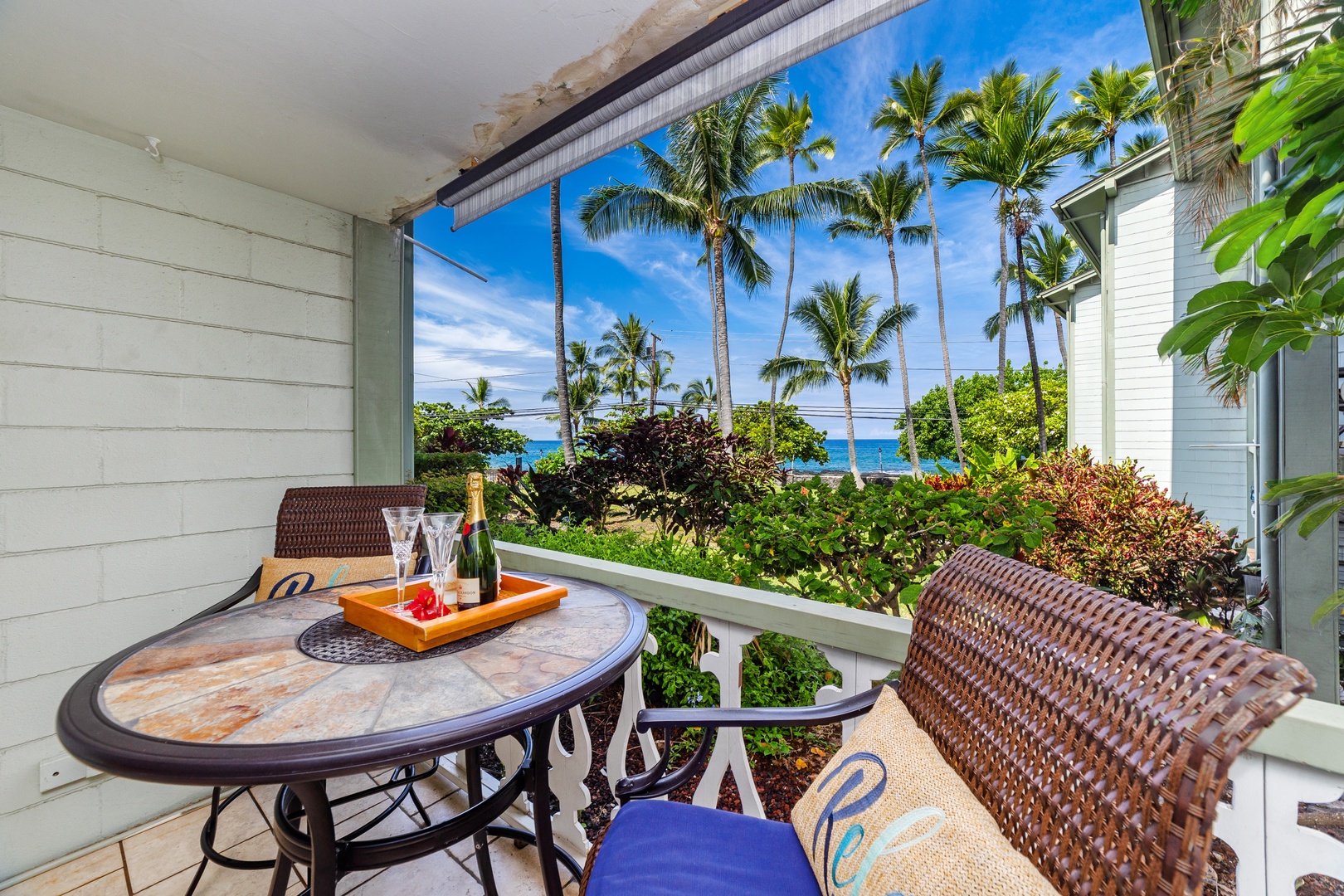 A serene oceanfront balcony with tropical palm trees and lush landscaping offers a perfect spot to enjoy your morning coffee or evening champagne while taking in stunning coastal views.