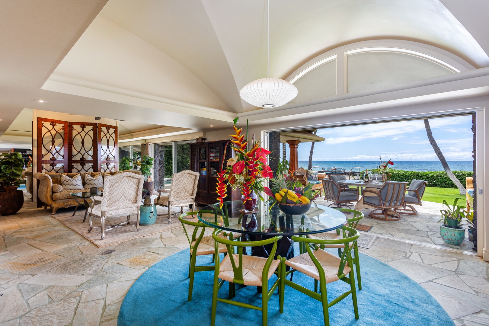 Dining/Living Area - Relax in your elegant living space with soaring ceilings and seamless indoor-outdoor flow to a stunning oceanfront lanai. Vibrant tropical décor and breezy coastal views invite pure serenity.
