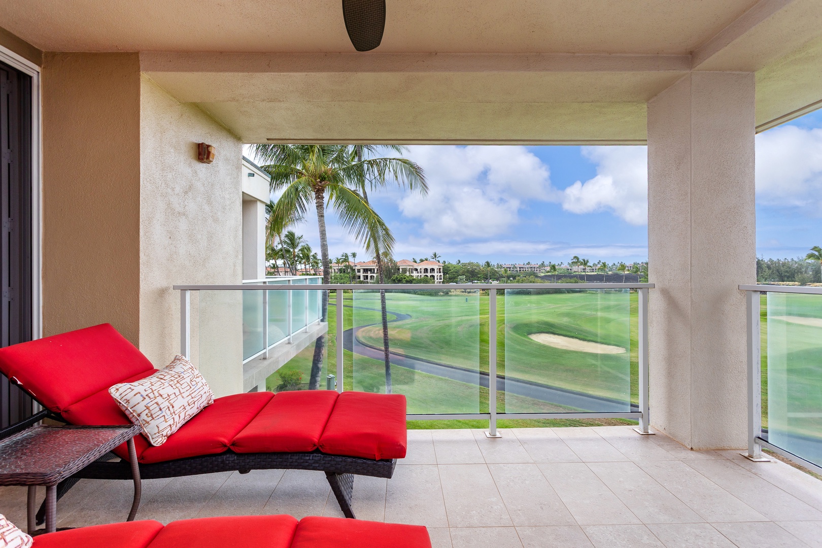 Relax on your private balcony with stunning golf course and palm tree views. Unwind on plush red loungers while soaking in the tropical breeze and serene landscape.