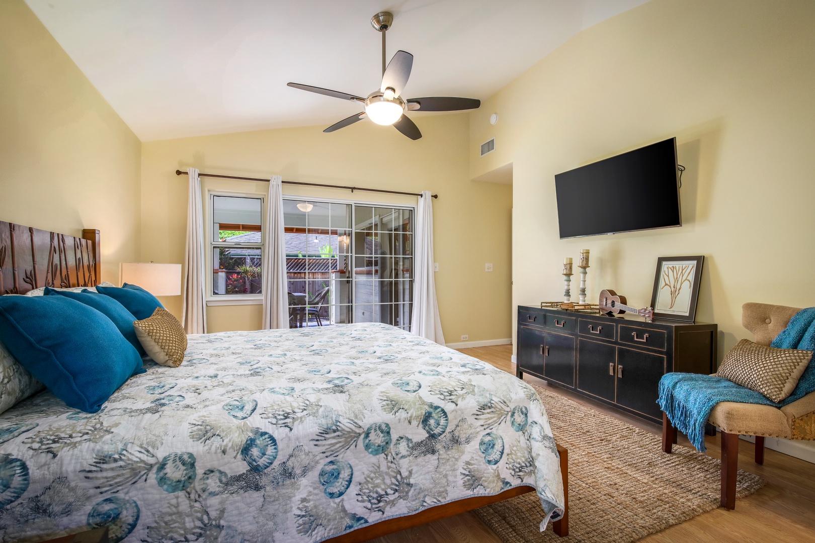 Your peaceful retreat features a plush bed with coastal-inspired linens, a large TV for unwinding, and sliding doors that open to your private patio—perfect for morning coffee or evening relaxation.