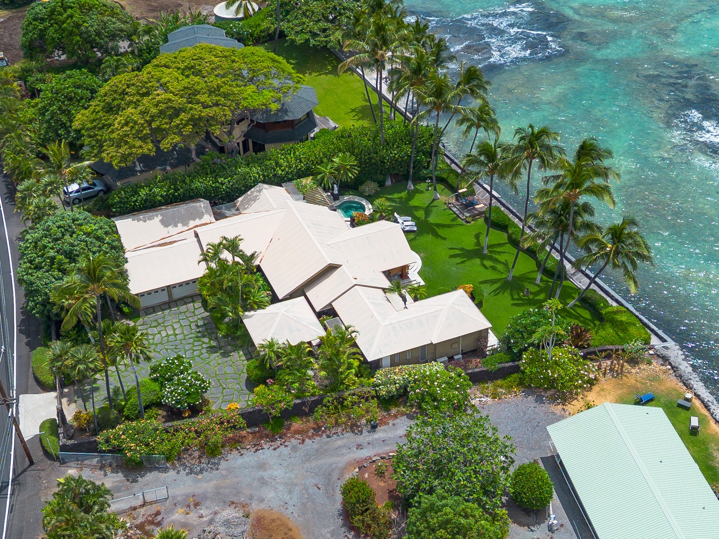 Oceanfront vacation home nestled on lush grounds with tropical landscaping, featuring multiple buildings, private plunge pool, and nearby access to crystal-clear turquoise waters along the coastline.