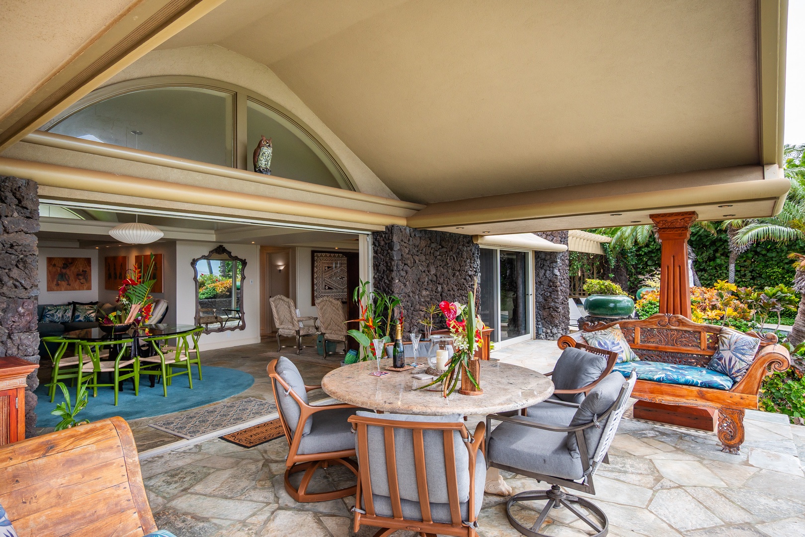 Relax in your covered lanai with comfortable seating, tropical blooms, and open-air dining—perfect for savoring island breezes surrounded by lush garden views.