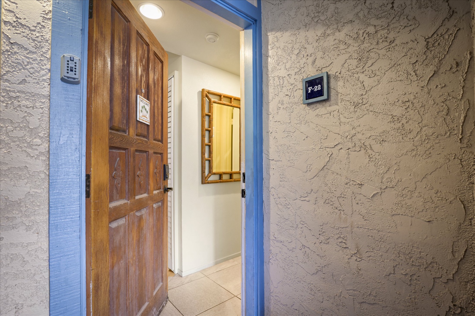 The entrance features a secure smart lock and bright blue trim that frames your private doorway. Inside, a welcoming space awaits with warm wood tones and natural light.