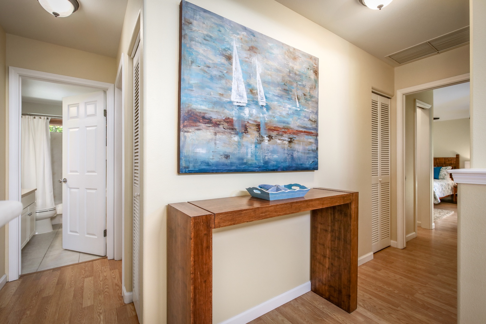 Bright hallway with coastal artwork connecting your private bathroom and bedroom—a thoughtful space that feels both relaxing and refined.