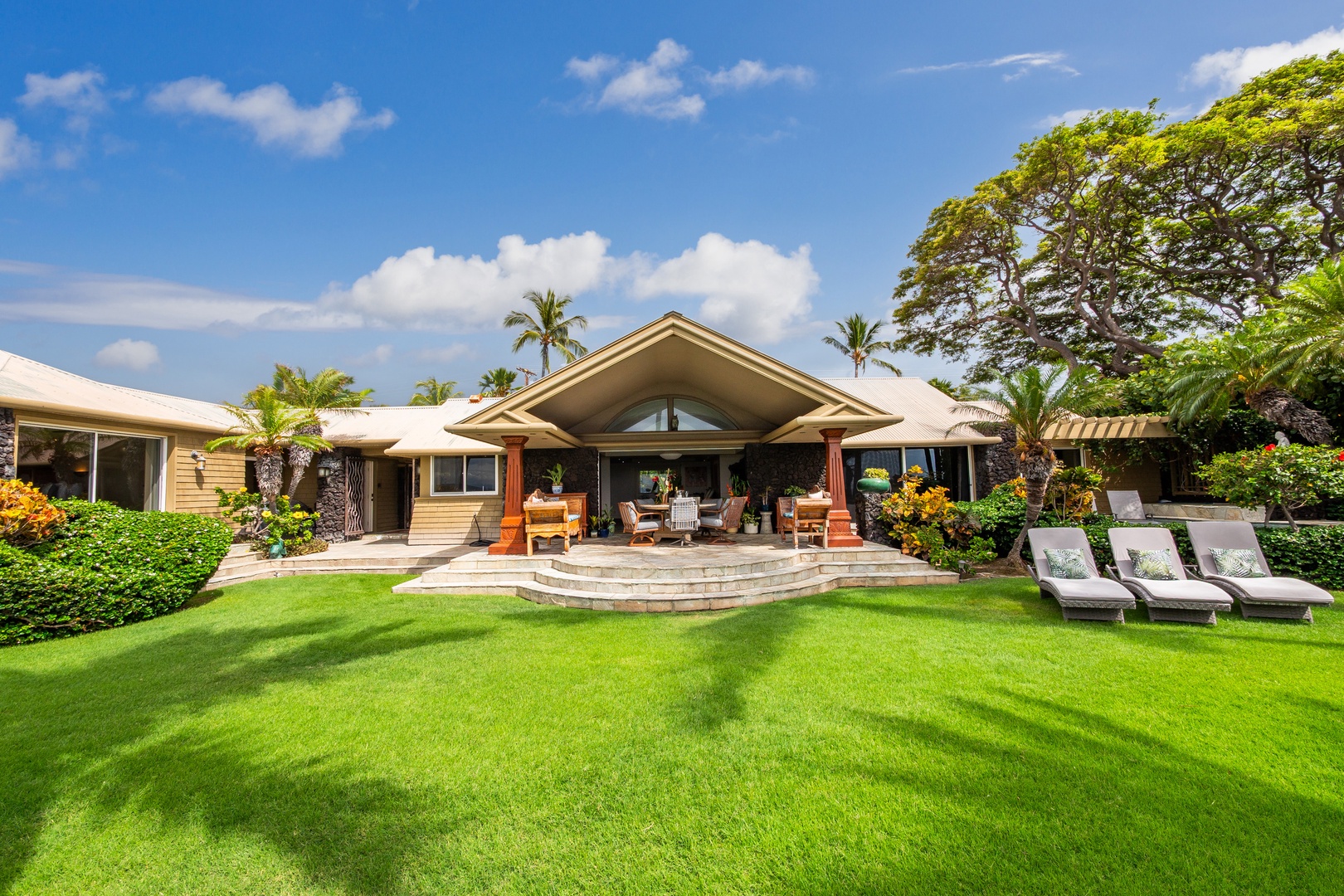 Tropical elegance meets island charm with lush lawns, palm trees, and a welcoming covered patio perfect for relaxing in paradise.