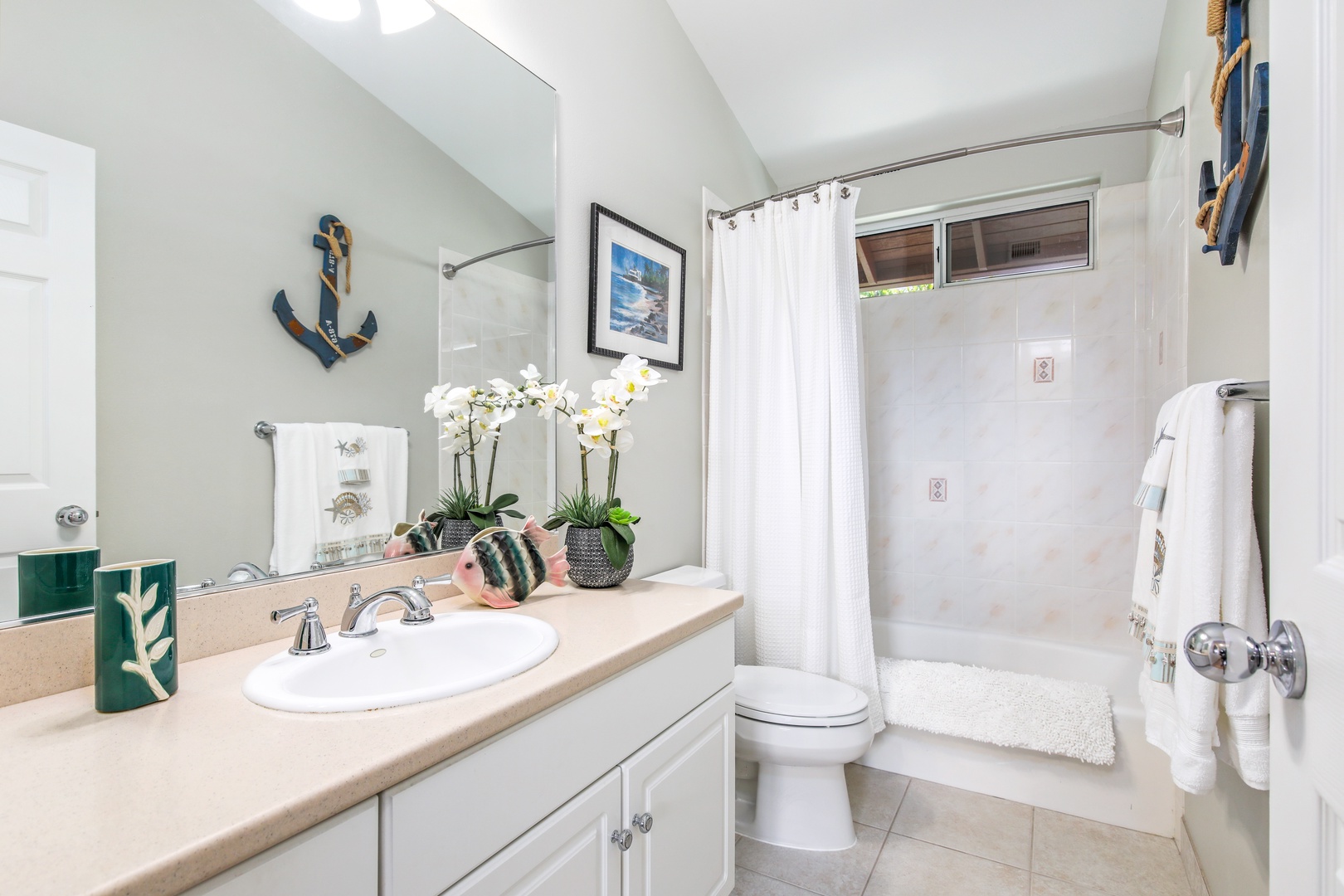 Picture yourself refreshing with a warm shower in this charming coastal bathroom. Natural light fills the space, while nautical touches and white orchids create a soothing retreat.