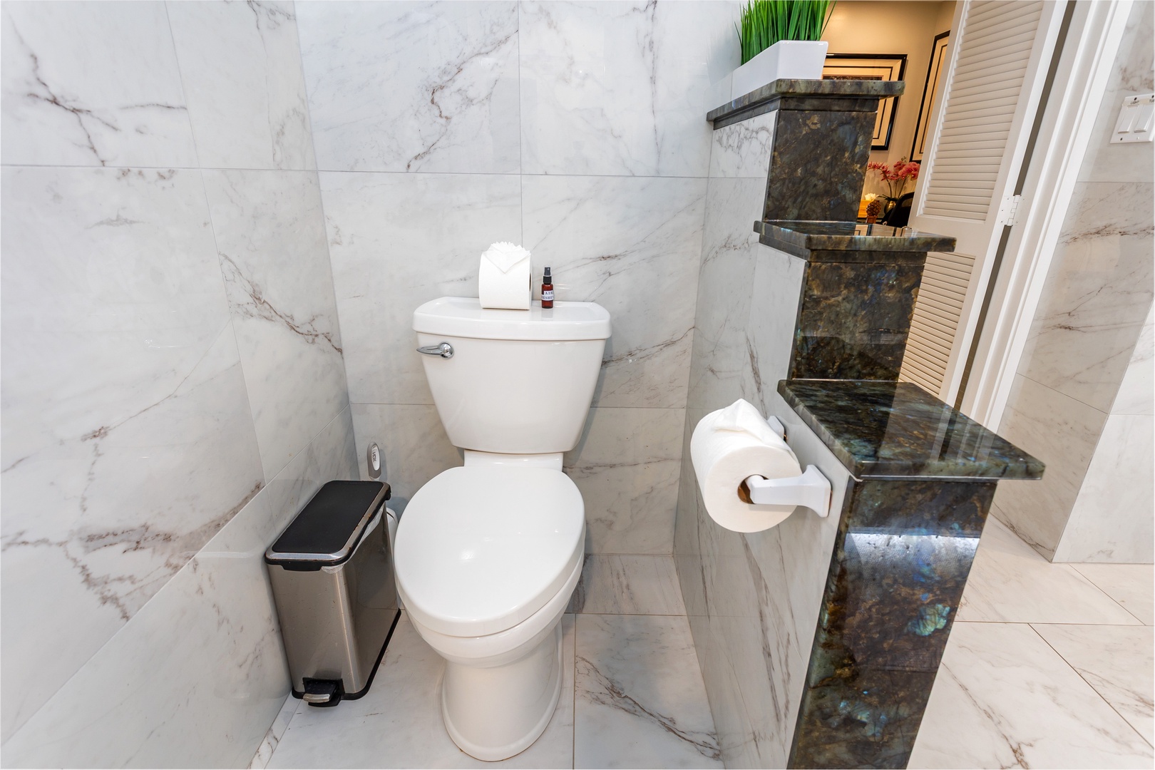 Spa-inspired bathroom featuring elegant marble-look tile walls, polished counters, and modern fixtures designed for your comfort and convenience during your stay.