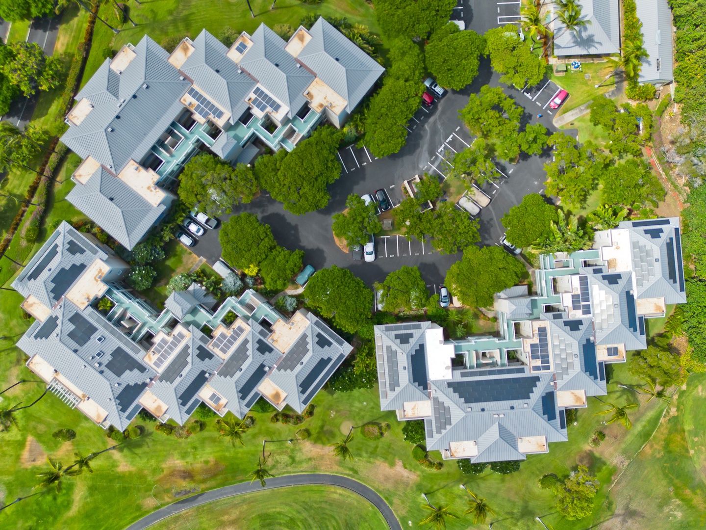 Aerial view of the rental complex nestled in lush tropical greenery with ample parking spaces and well-maintained grounds providing a peaceful resort-like setting.