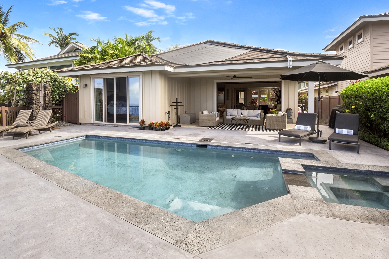 Modern vacation home with private swimming pool, covered lanai seating area, and tropical landscaping in a peaceful residential setting.