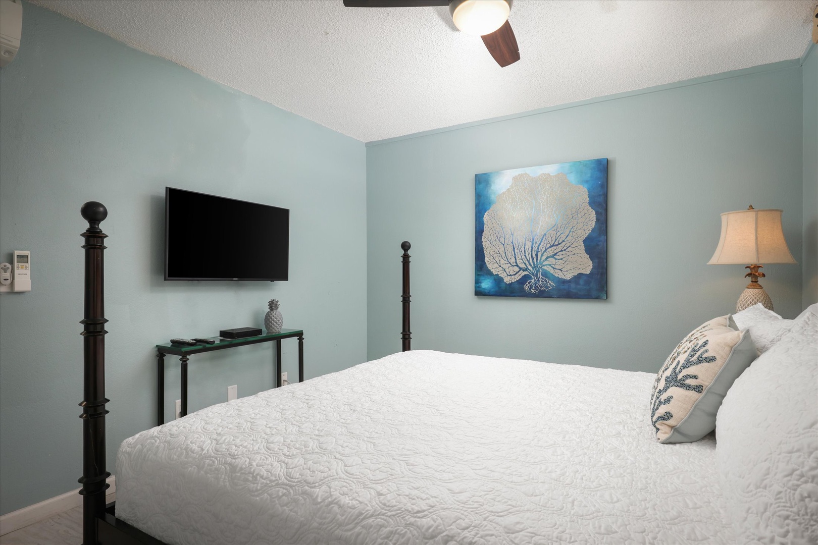 Unwind in your serene coastal-themed bedroom with a plush bed, smart TV, and ocean-inspired artwork. The soothing blue tones create a tranquil retreat for your restful nights.