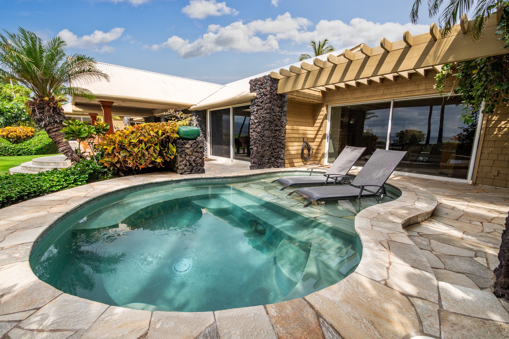 Enjoy your plunge pool, stone deck, and tropical landscaping under sunny skies.