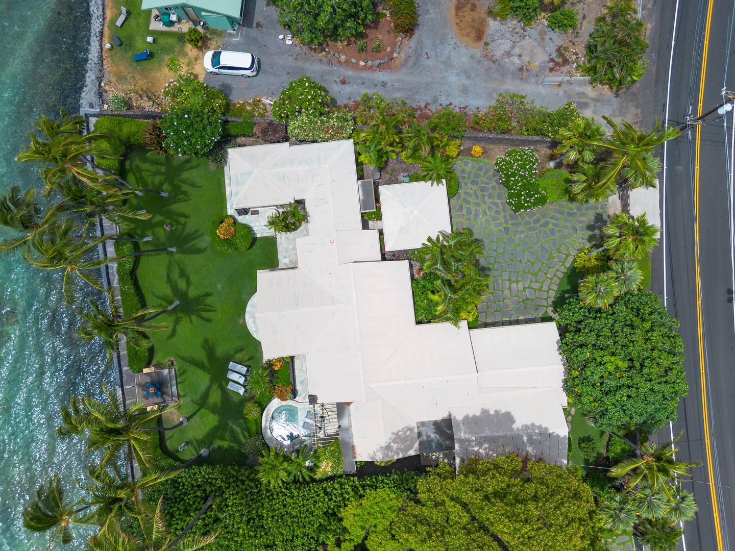 Aerial view of a coastal vacation property nestled among lush tropical palms, with nearby oceanfront access.