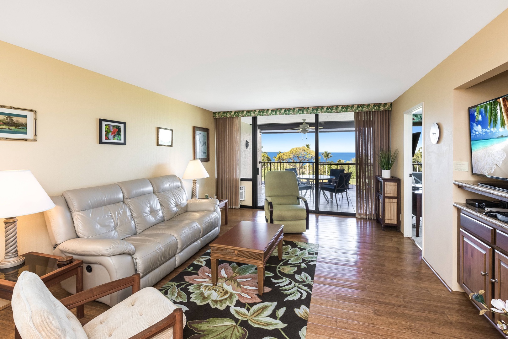 Unwind in your airy living room, where soft leather seating, warm wood floors, and ocean views through your private lanai create the perfect Hawaiian retreat.