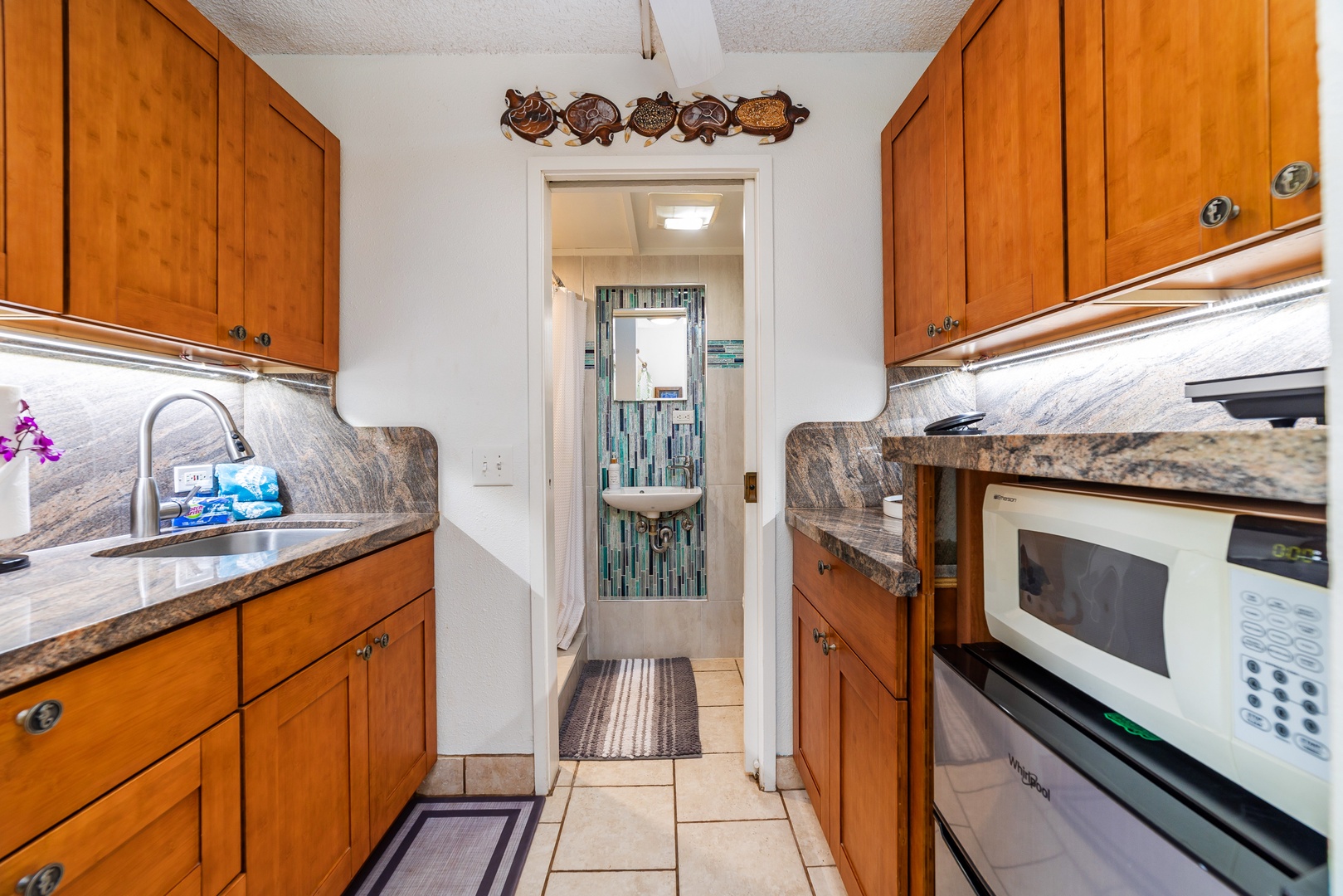Step into a nicely equipped kitchenette featuring warm wood cabinetry, granite countertops, and under-cabinet lighting. Your microwave, sink, and all the essentials await for easy meal prep during your stay.