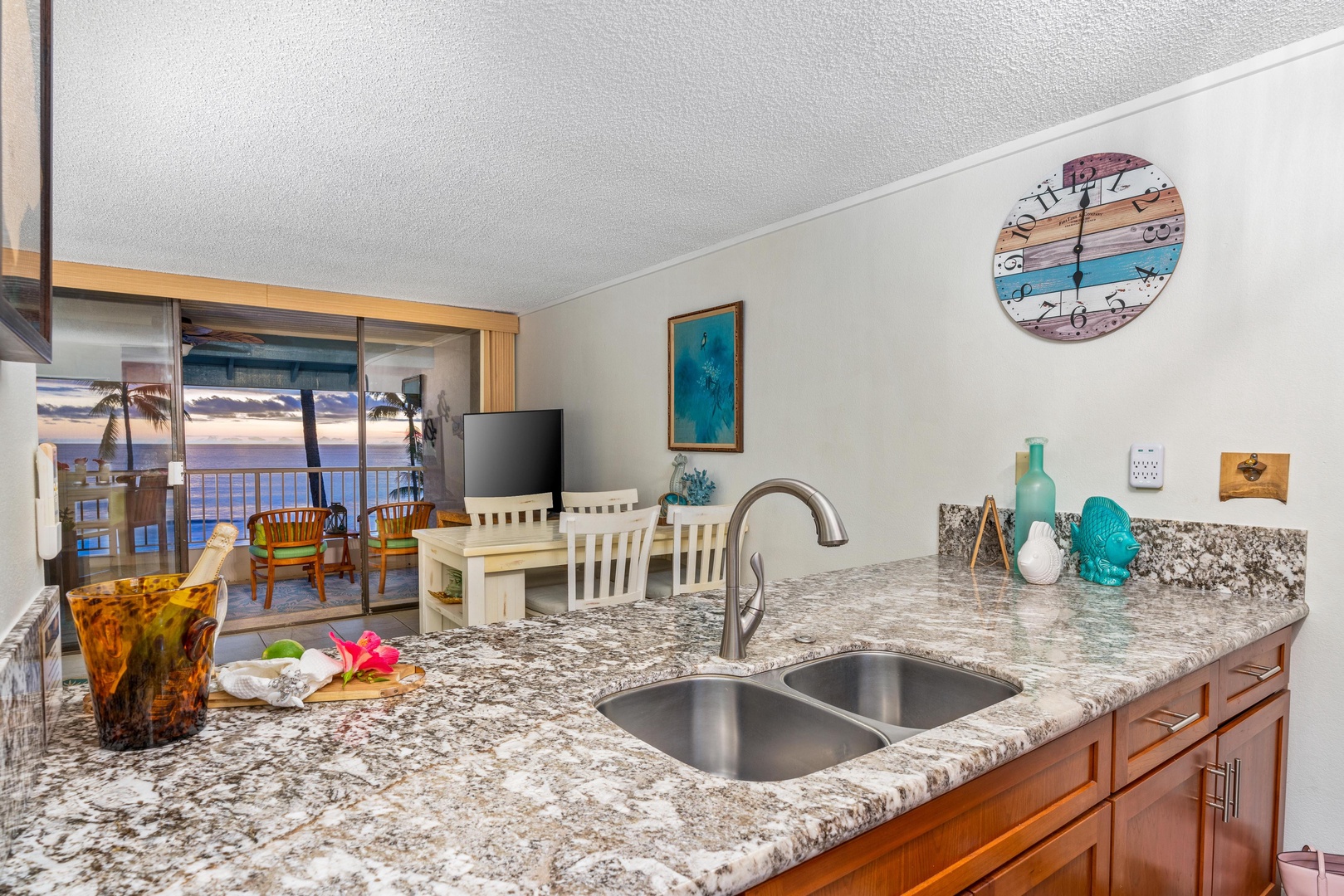 Your open kitchen features gleaming granite counters and a double sink, flowing seamlessly into a bright living space with sunset views from your private lanai.