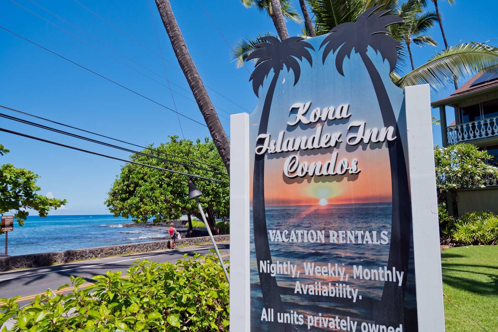 Kona Islander Inn Condos sits steps from the sparkling ocean, with palm trees swaying overhead and lush greenery framing the oceanfront property. This beachside retreat marks your arrival to island paradise.