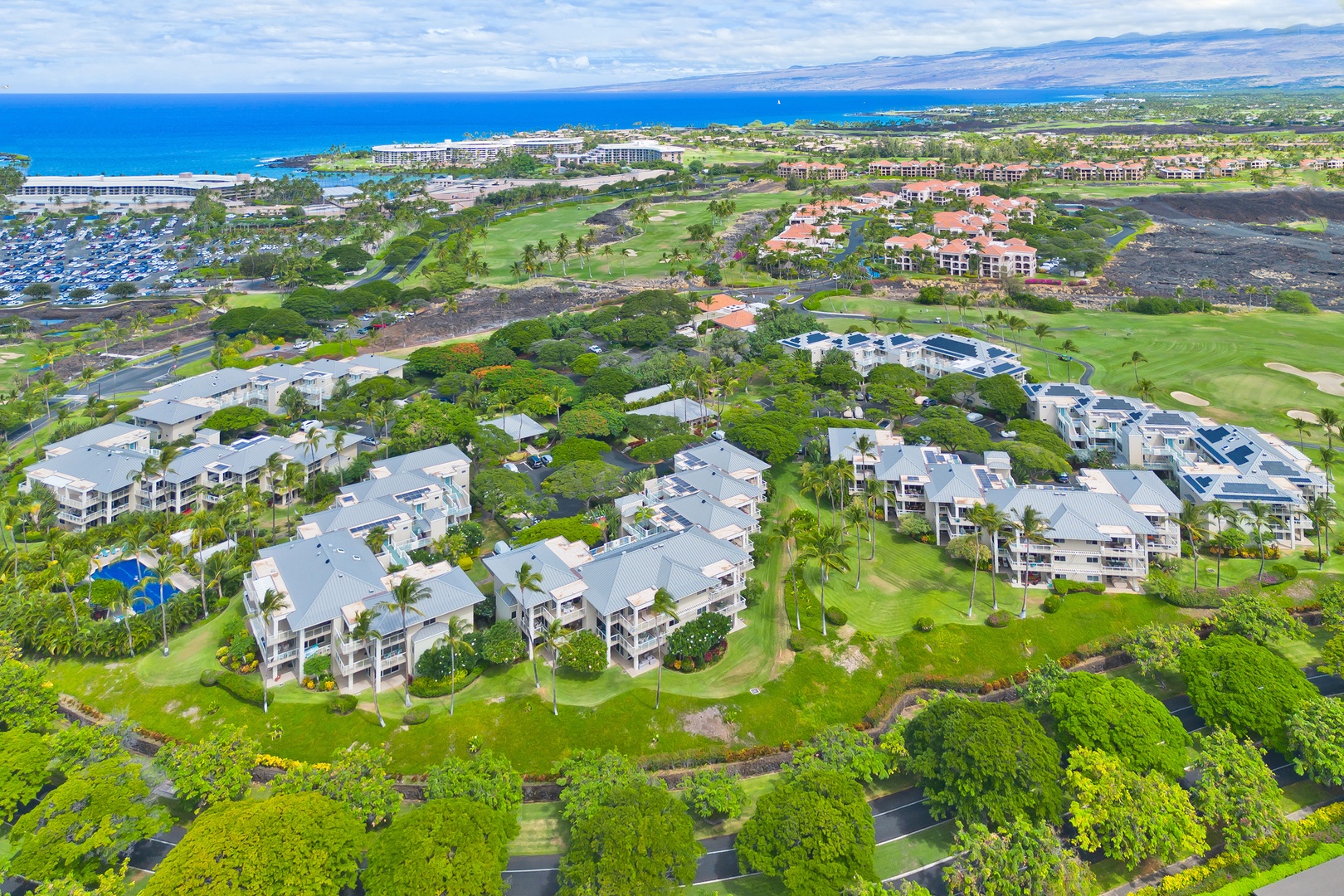 Aerial view of an oceanfront resort community featuring vacation rentals, golf course fairways, and dramatic coastline with pristine beaches along the horizon.
