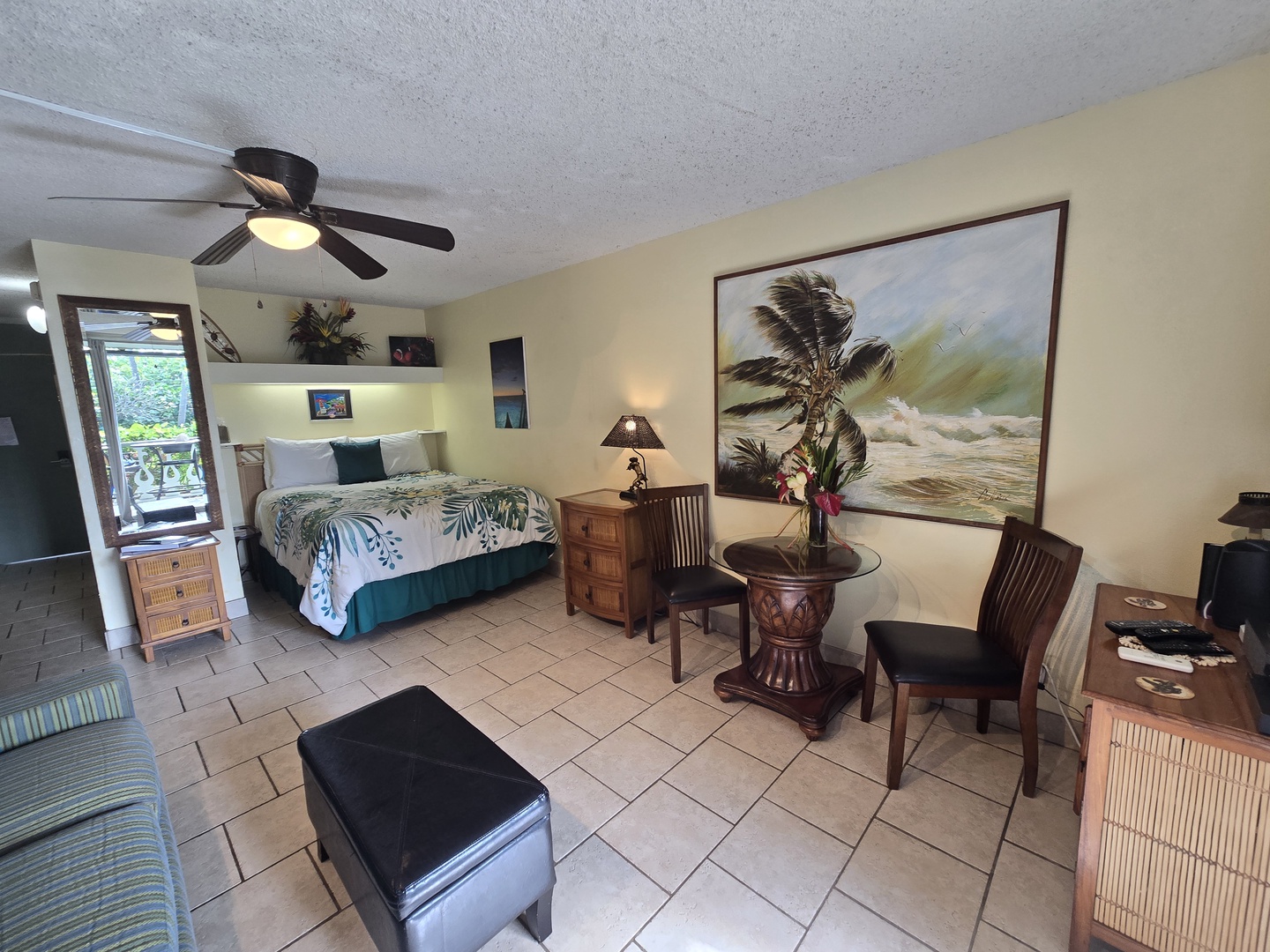 Unwind in your tropical-themed studio with comfy seating, island decor, and a ceiling fan keeping you cool.