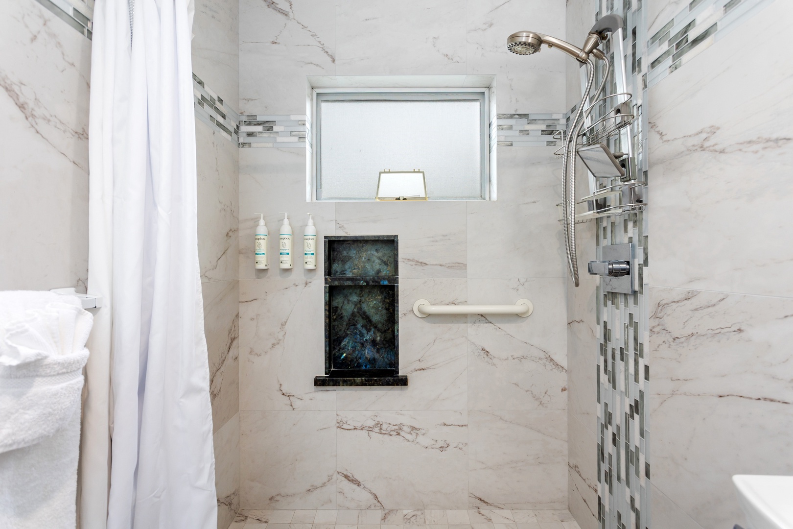 Elegant marble-accented shower with grab bars and handheld fixtures ensures your comfort and safety, featuring spa-quality amenities and thoughtful accessibility design throughout.
