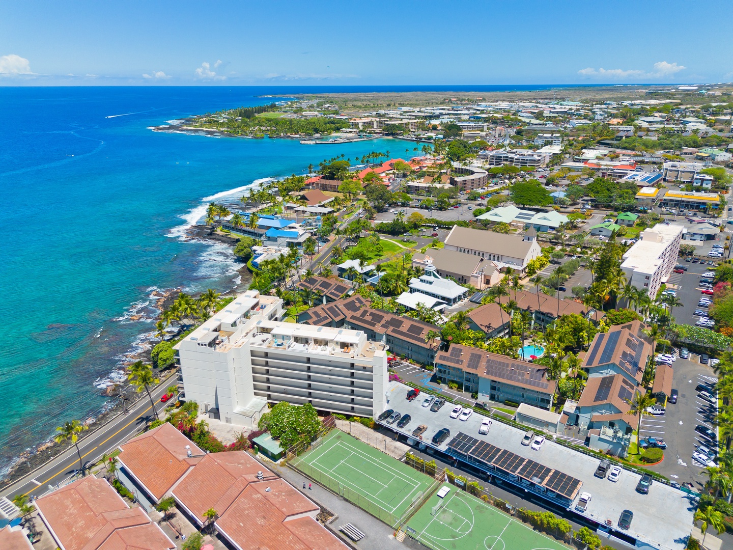 Aerial view of a coastal vacation property nestled along turquoise waters, surrounded by lush tropical landscaping and convenient nearby amenities in a vibrant island community.