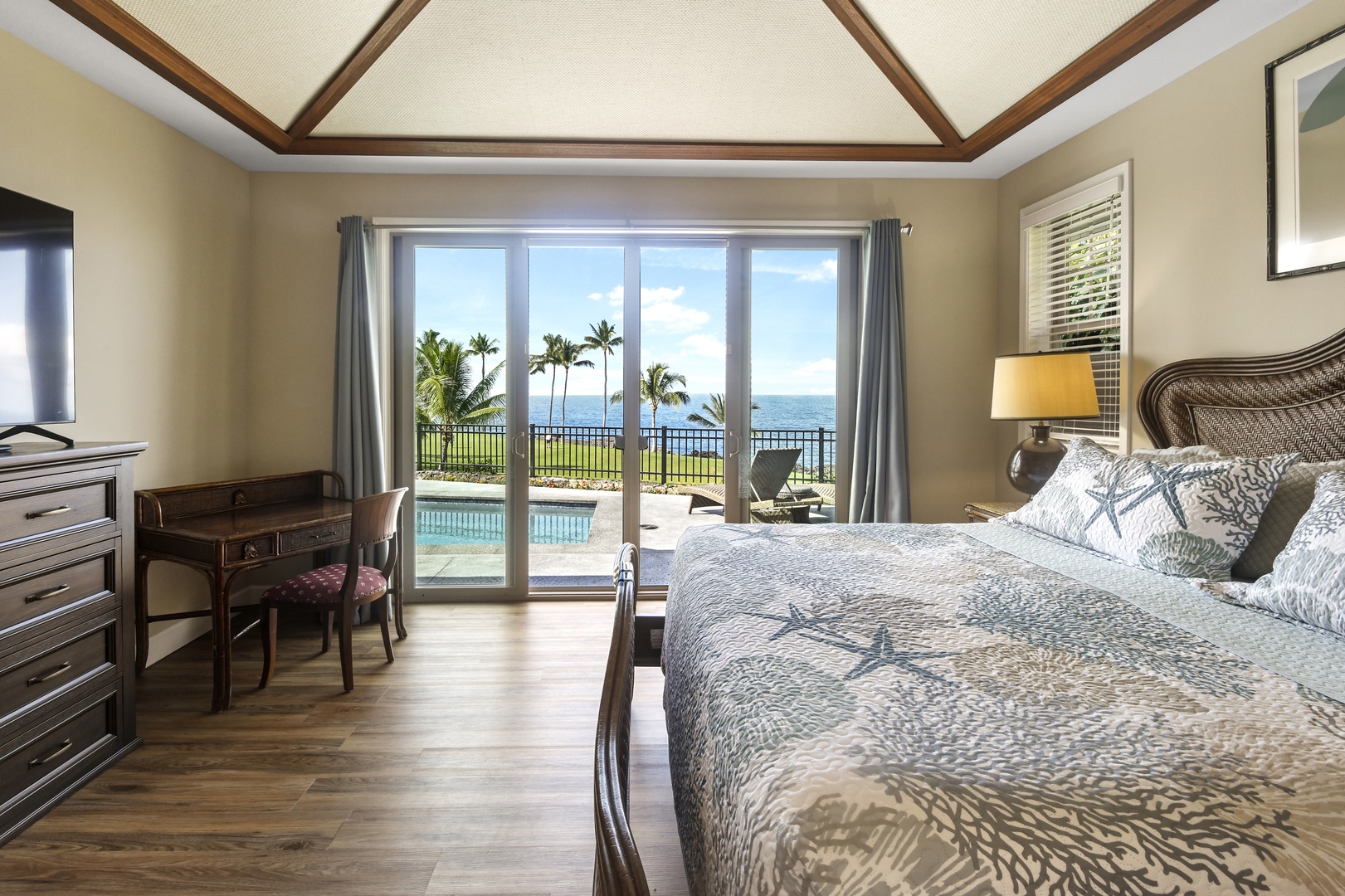 Wake up to stunning ocean views through floor-to-ceiling sliding glass doors, with direct pool access from your elegant tropical bedroom.