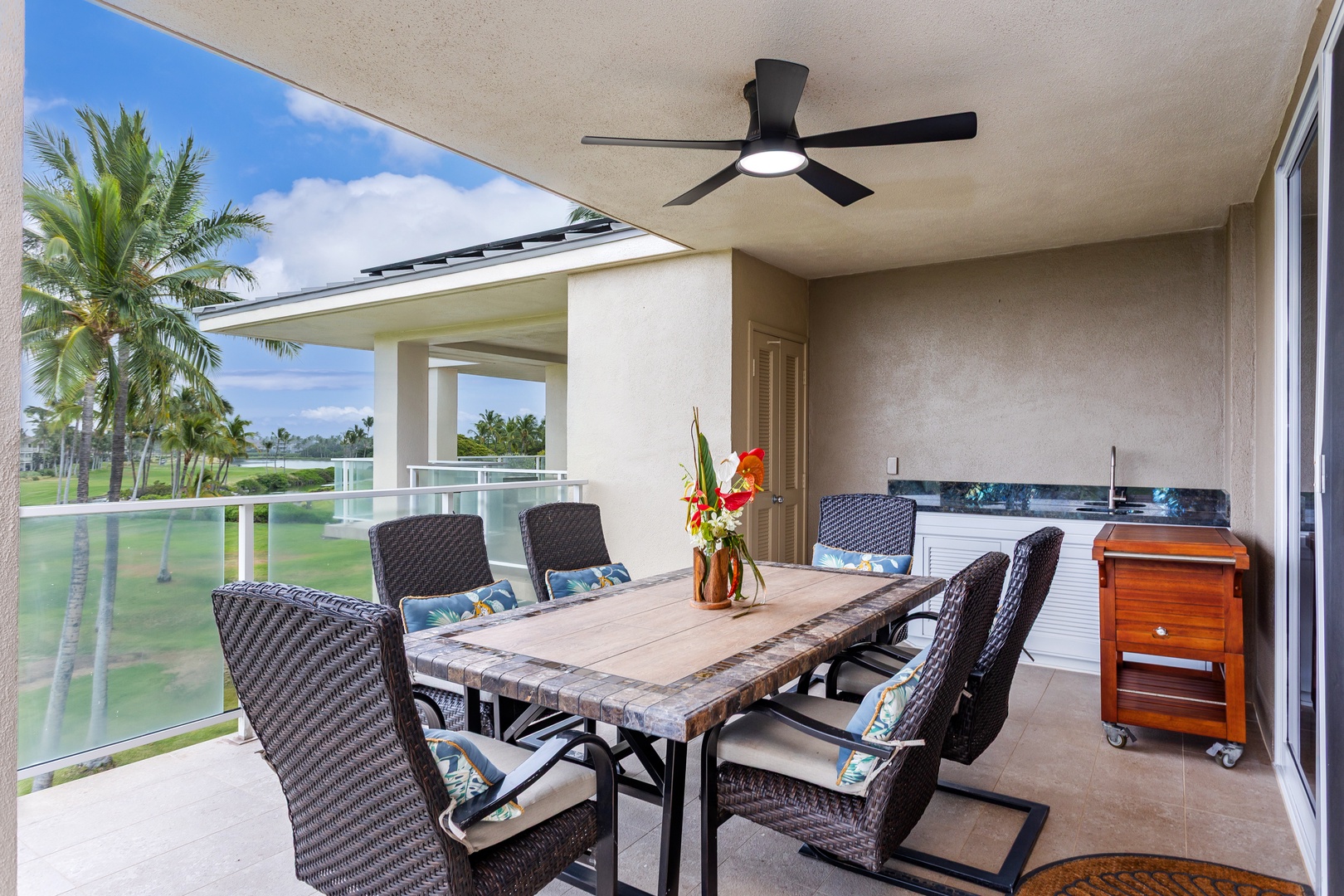 Your covered lanai invites you to dine alfresco under the ceiling fan's gentle breeze, with a full outdoor kitchen setup and sweeping golf course and palm tree views framing every meal.