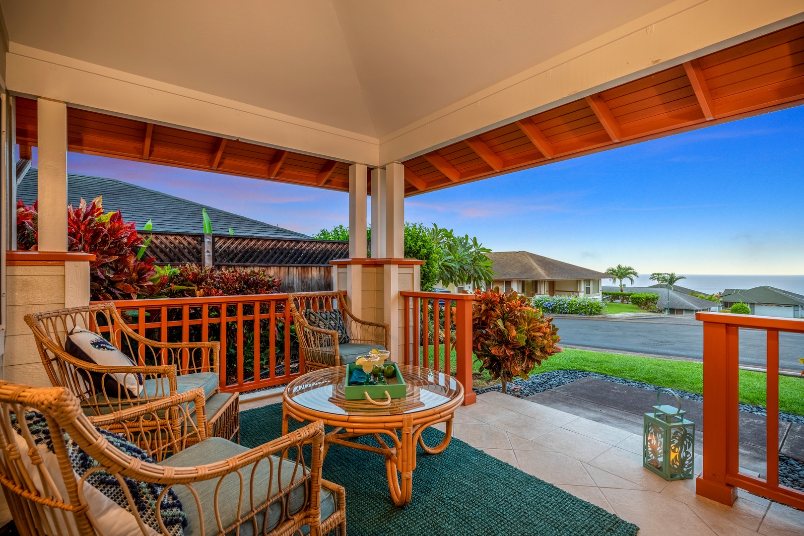 Step onto your private covered lanai where rattan seating invites morning coffee or sunset relaxation. The tropical foliage and distant ocean views create a serene island escape.