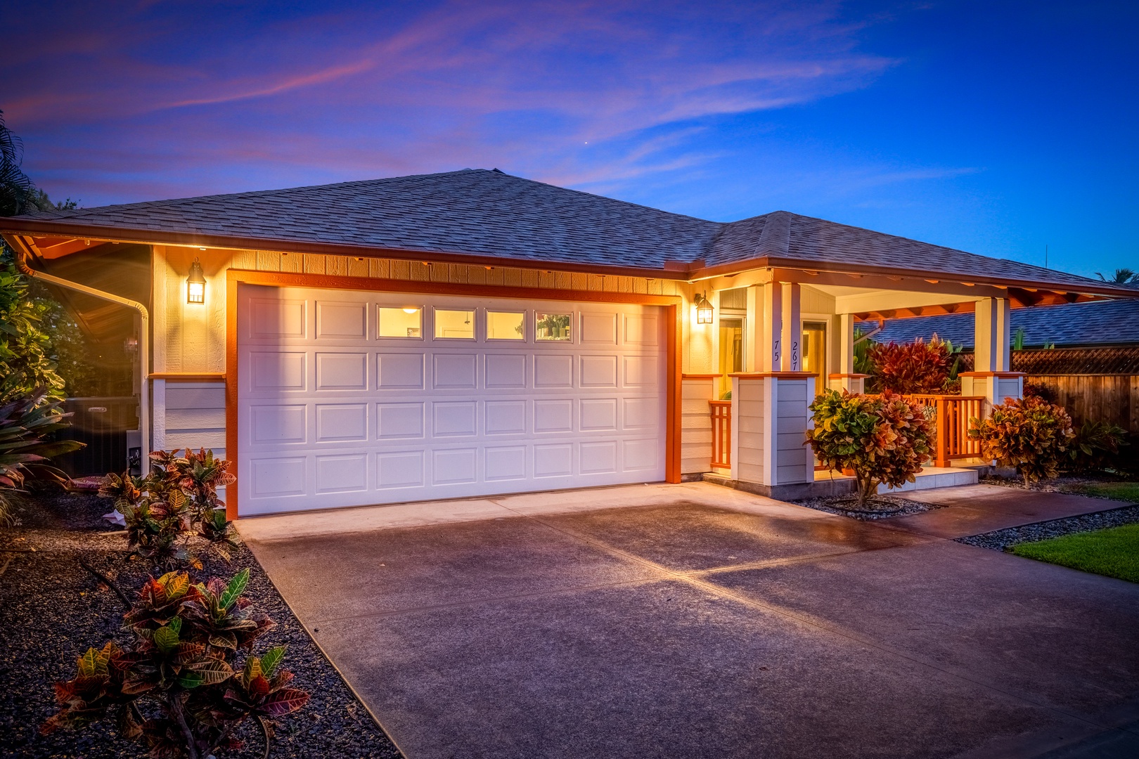 This vacation rental's warm exterior lighting and inviting Hawaiian architecture create a welcoming first impression as twilight approaches, set against a stunning tropical sky.