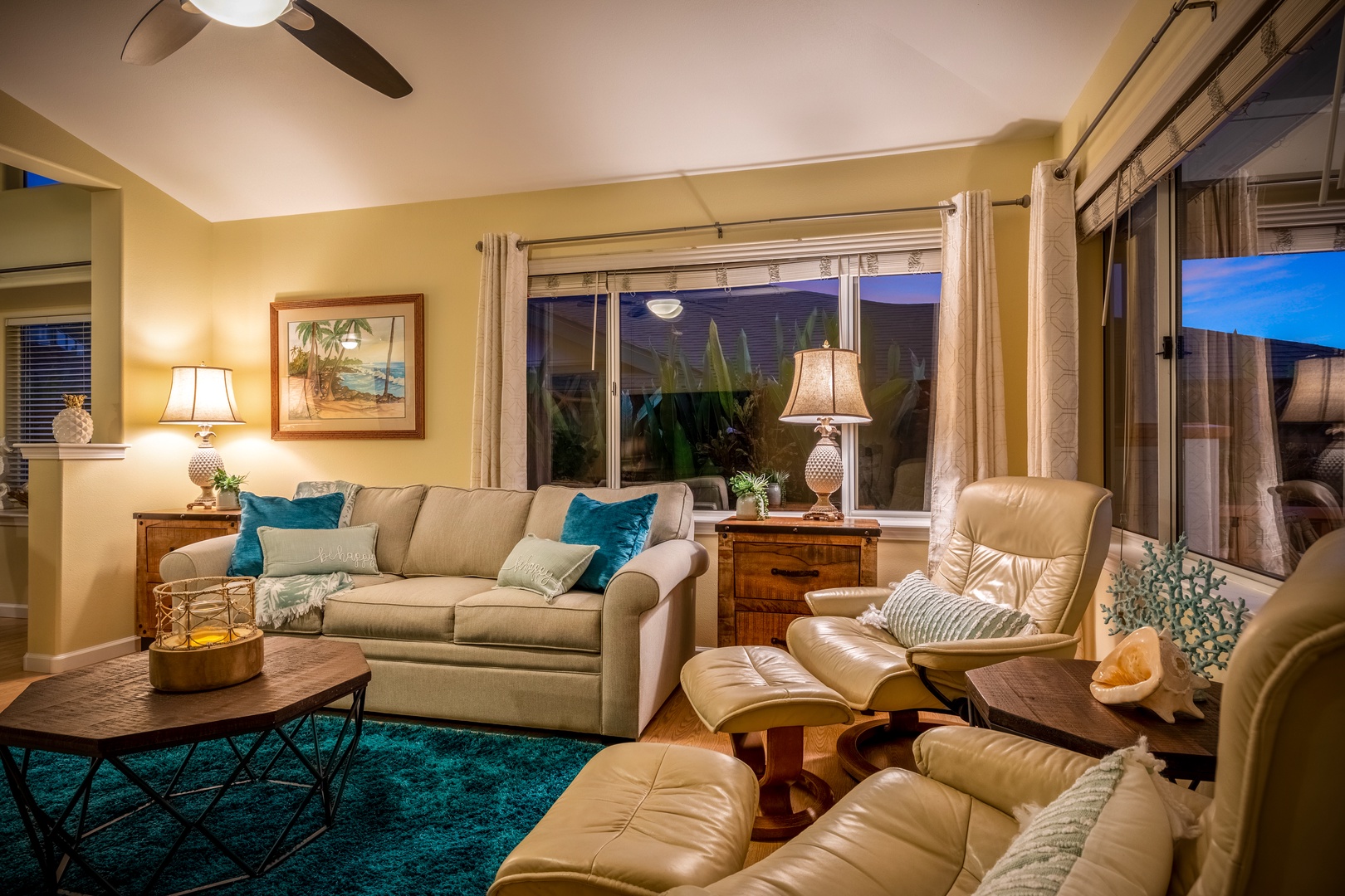 Sink into plush seating with vibrant tropical accents as warm lighting and a gentle ceiling fan create your perfect retreat for evening relaxation.