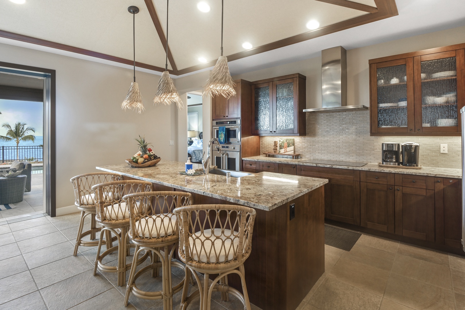 You'll love preparing meals in this elegant kitchen featuring rich wood cabinetry, granite countertops, and tropical-style seating perfect for casual dining.