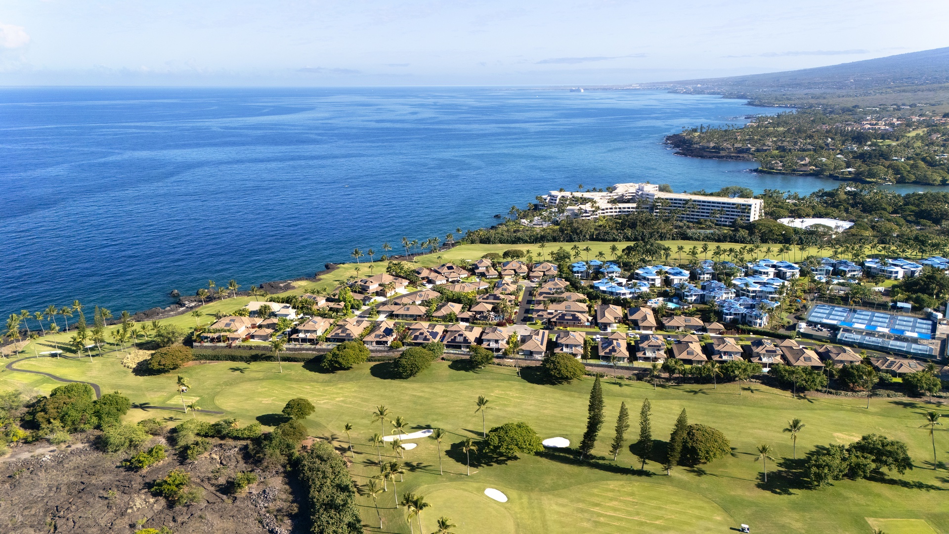 Aerial view showcasing the Holua Kai resort community with golf course, residential villas, and pristine Hawaiian coastline.