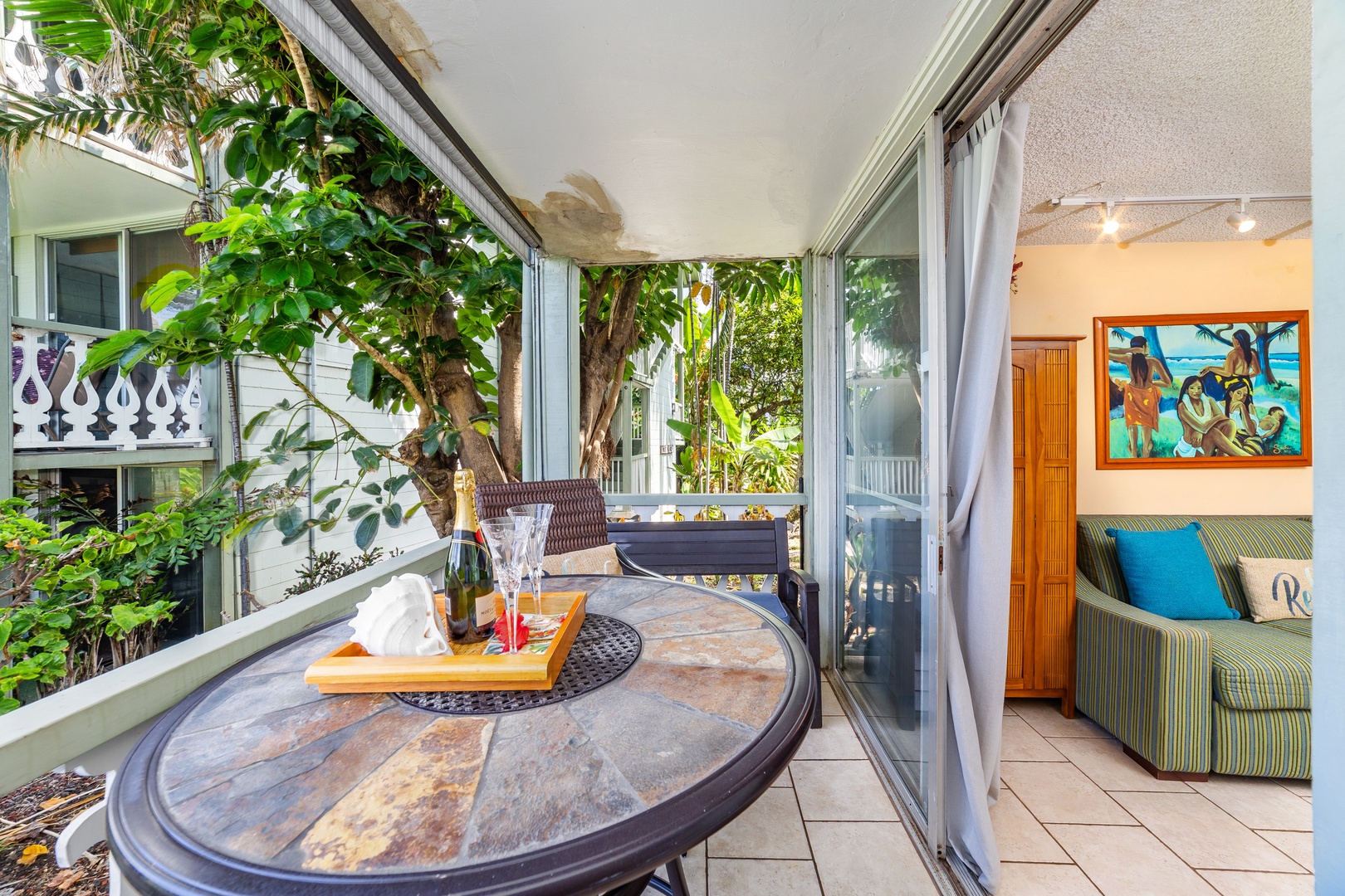 Step onto your private lanai where morning coffee or evening cocktails feel even more special, surrounded by tropical greenery and a cozy outdoor table perfect for two.