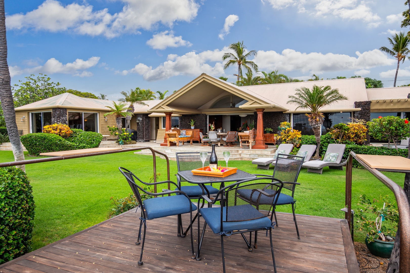 This spacious Hawaiian estate features multiple covered lanais and open-air seating areas surrounded by manicured tropical gardens, with palm trees and ocean breezes creating an authentic island atmosphere throughout the property grounds.