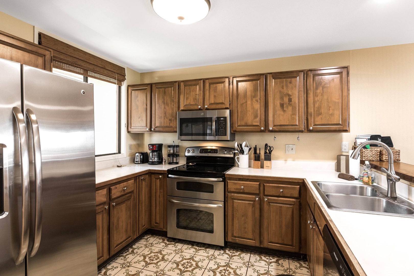 Your spacious kitchen features warm wood cabinetry, stainless steel appliances, and charming patterned tile flooring—everything you need to prepare favorite meals in comfort and style.