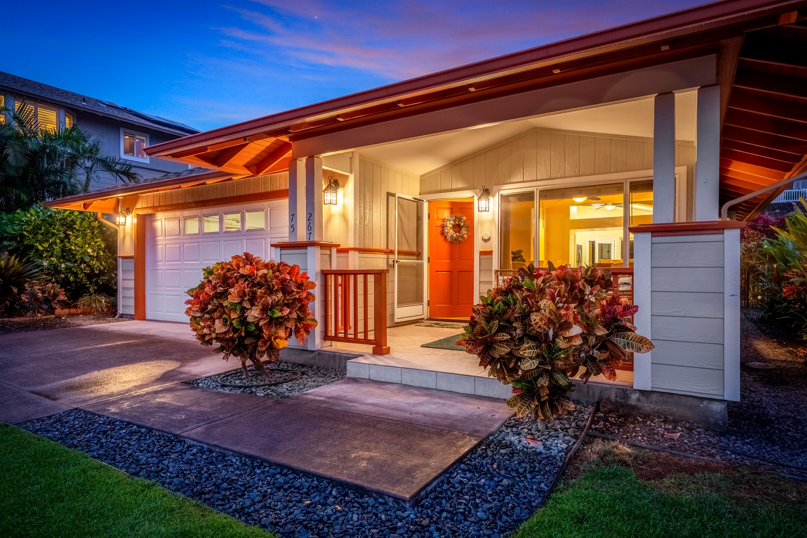Modern tropical home featuring warm architectural lighting, landscaped entryway, and inviting covered porch, situated in a peaceful residential neighborhood perfect for your Hawaiian getaway.