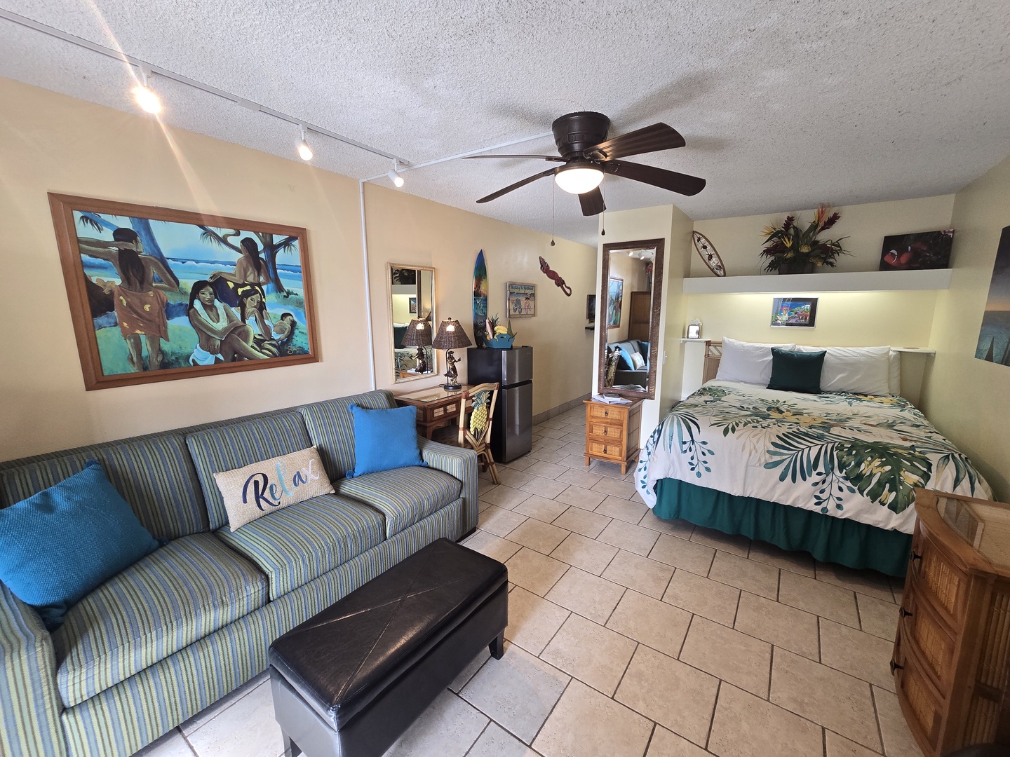 Your tropical studio blends comfort with Hawaiian charm - relax on the striped sofa or unwind in the cozy bed under gentle ceiling fan breezes.