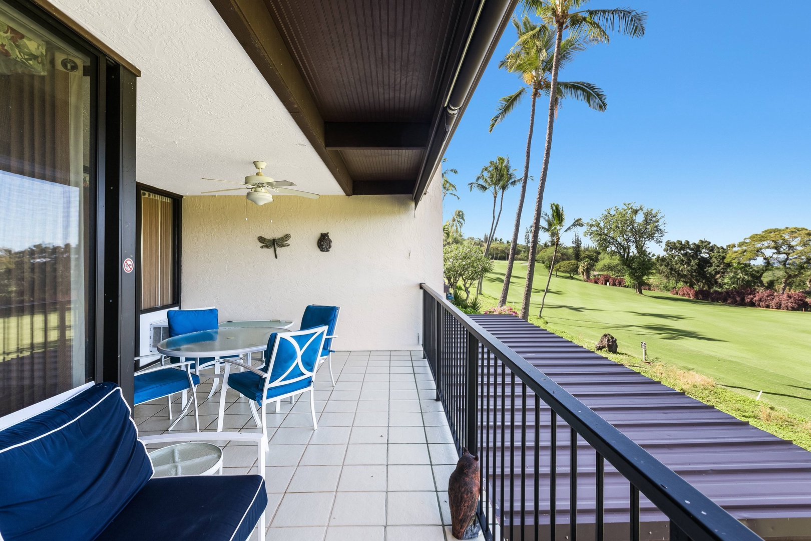 A covered balcony overlooks a lush golf course and tropical landscape, providing a tranquil setting for morning coffee or evening relaxation.