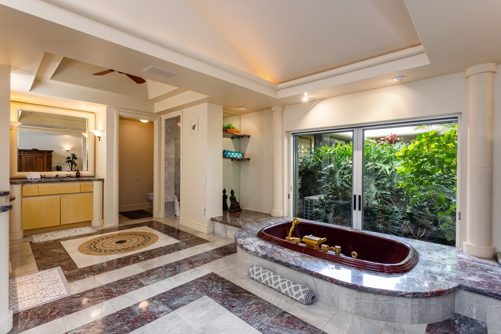 Primary Bathroom - Picture yourself unwinding in this luxurious marble bathroom, complete with a stunning soaking tub overlooking lush tropical greenery through expansive sliding doors.