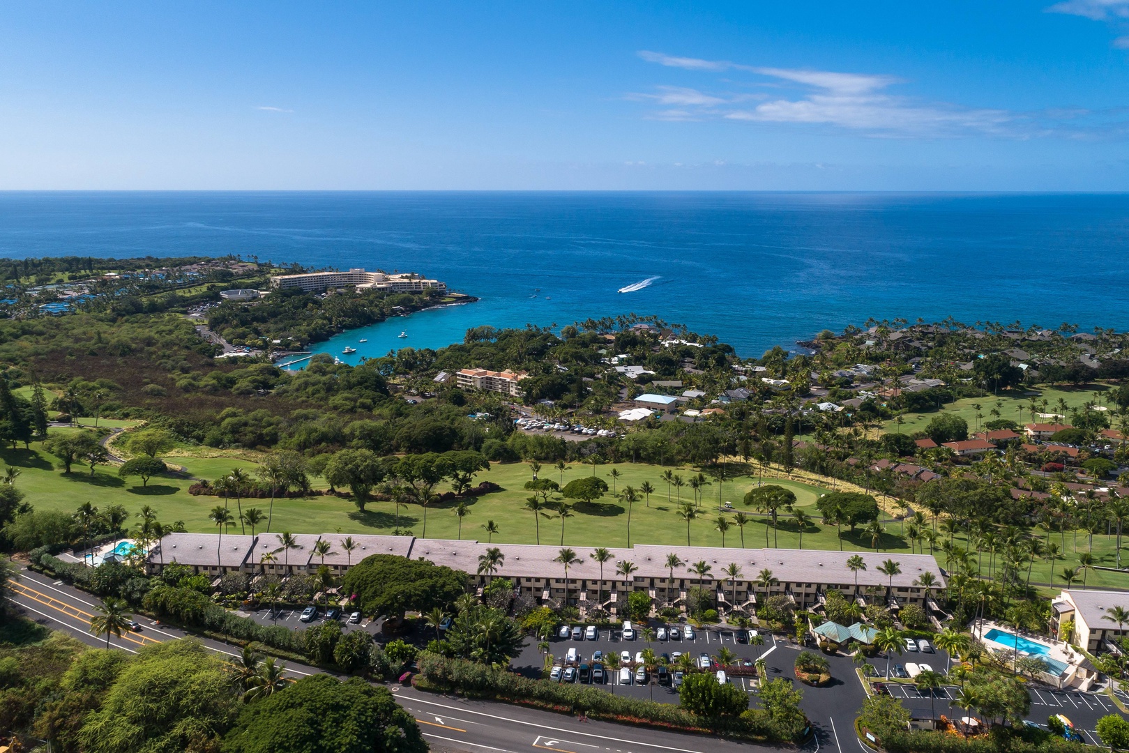 An aerial view showcasing the property nestled between lush golf courses and the sparkling turquoise coastline. The resort complex sits amid tropical landscaping with easy access to beaches, palm-lined greens, and oceanfront amenities.