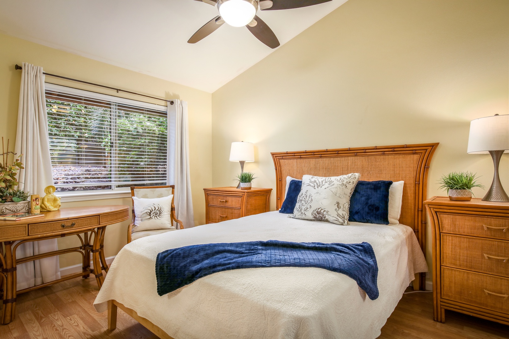 Your peaceful retreat awaits with a plush bed, warm bamboo furnishings, and a ceiling fan to keep you cool. Natural light streams through the window, while elegant lamps create the perfect evening ambiance.