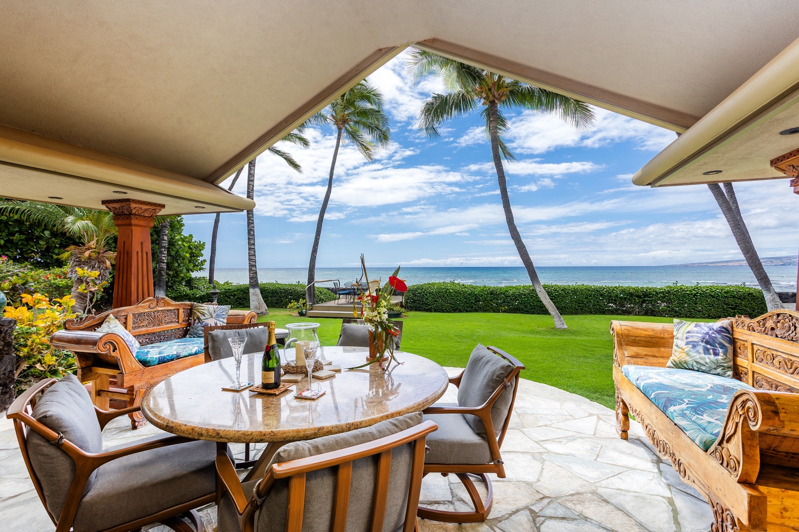 Savor your morning coffee at this oceanfront lanai, where swaying palms frame endless ocean views and lush lawns meet the shore—your private slice of paradise.