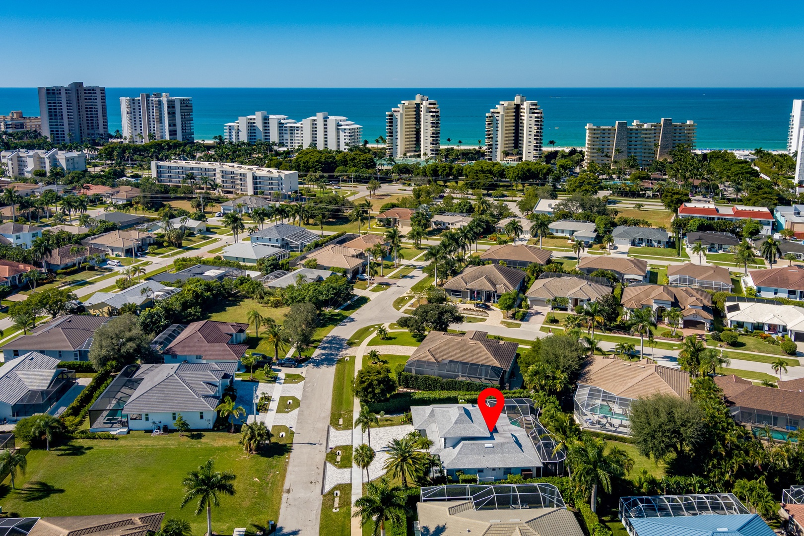 Stunning aerial view of a coastal neighborhood with tropical palms, residential homes, and pristine beaches just minutes away.