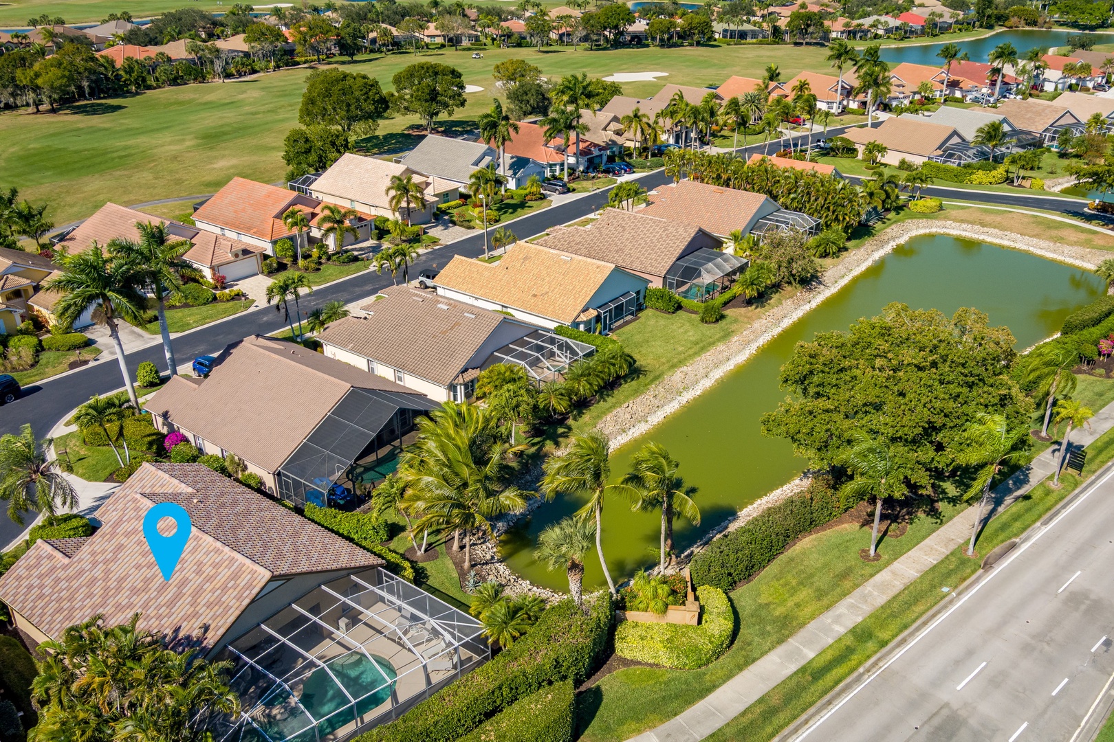 Aerial view of a residential community featuring waterfront homes with pools, surrounded by lush landscaping and golf course fairways.