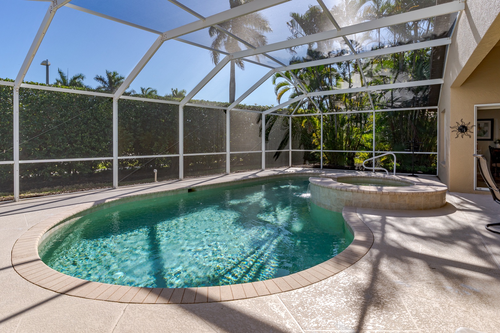 Step into your private oasis with sparkling pool and bubbling spa, sheltered under a bright screened lanai surrounded by tropical palms.