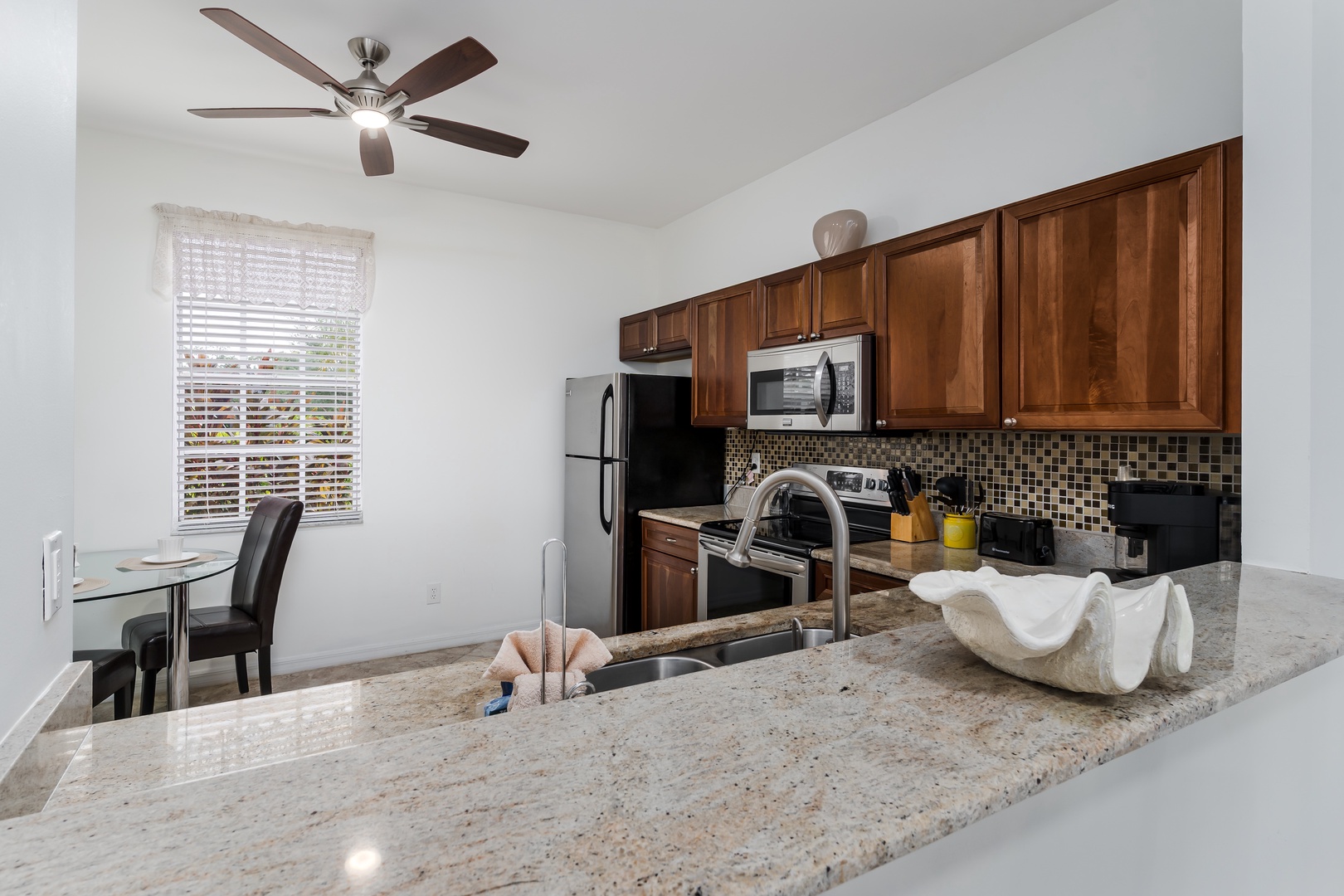 Your fully equipped kitchen awaits with sleek granite counters, warm wood cabinetry, and stainless appliances—everything you need to whip up a meal or just enjoy morning coffee at the cozy dining nook.