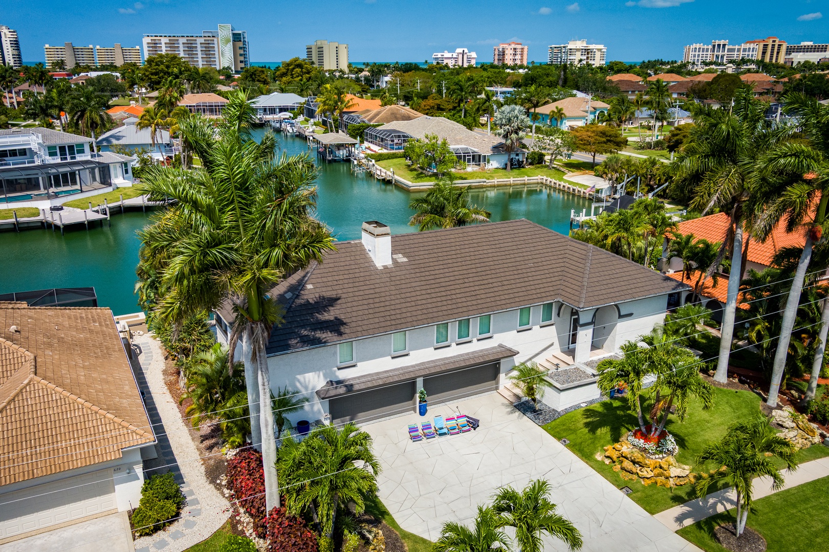 Modern waterfront property situated along a serene canal in a tropical coastal neighborhood, surrounded by palm trees and offering boat access to nearby beaches.
