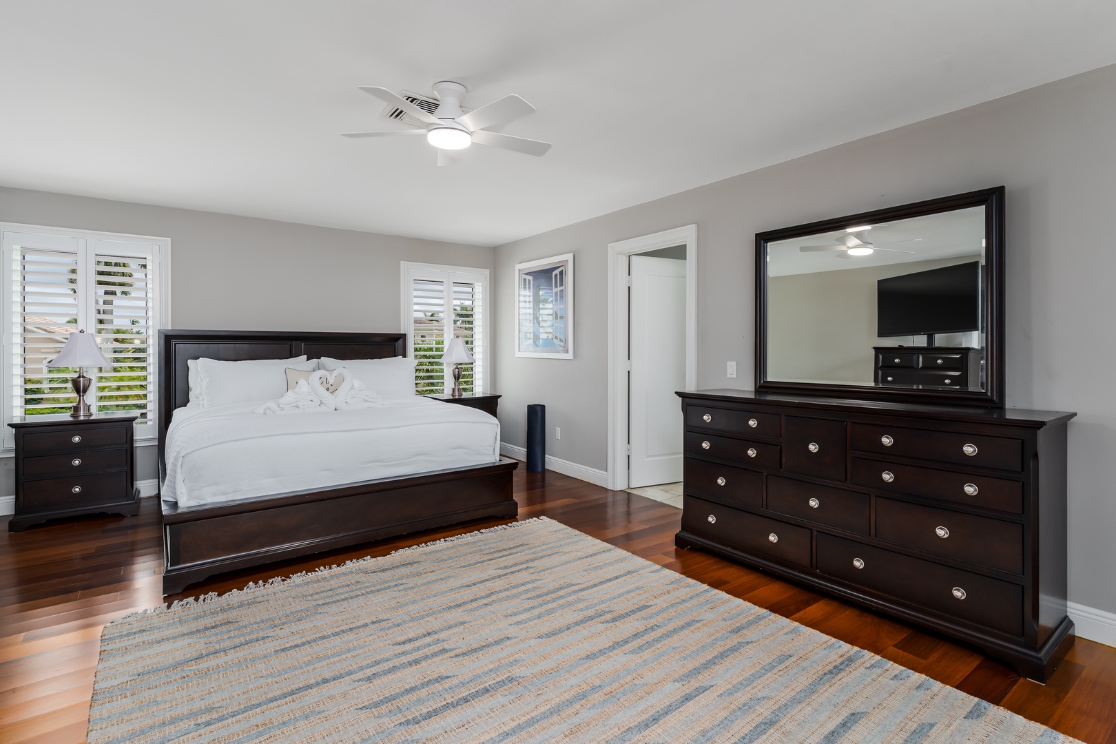 Your serene bedroom retreat features a plush bed with crisp linens, rich hardwood floors, and elegant dark furniture creating the perfect space to unwind after your adventures.