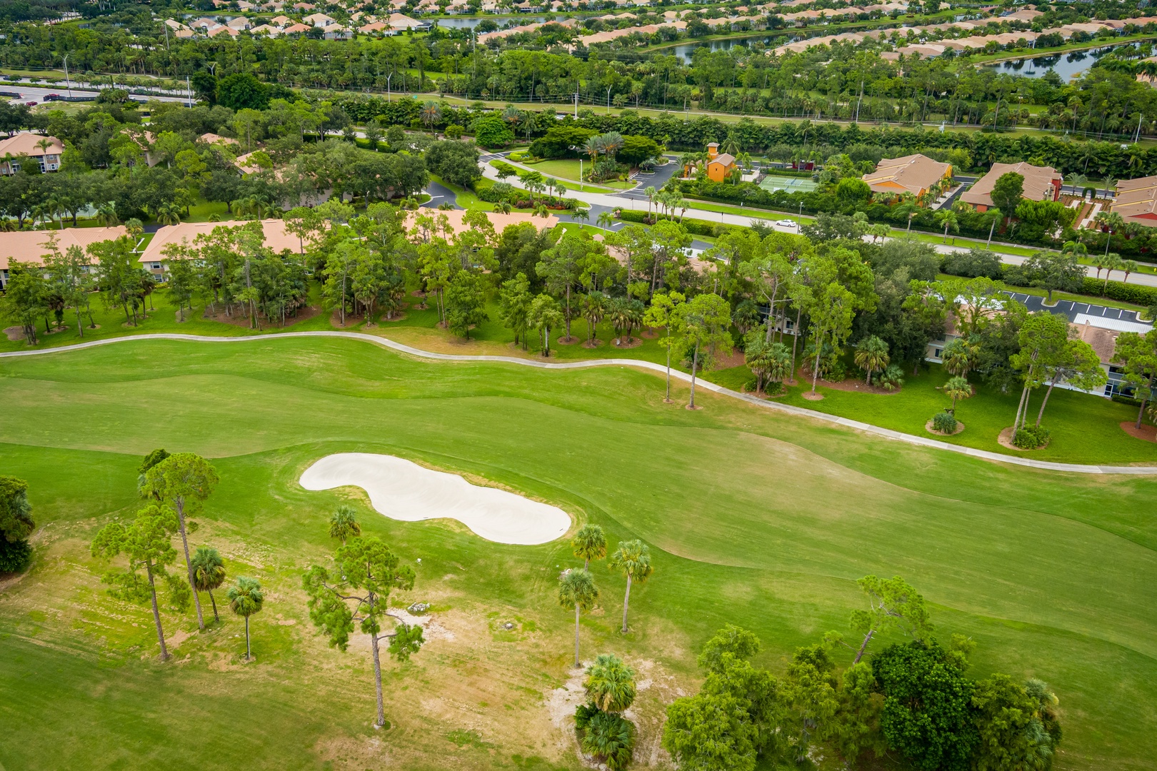 Aerial view of the property nestled within a lush golf community, surrounded by manicured fairways, serene water features, and abundant tree-lined streets that define this tranquil residential neighborhood.