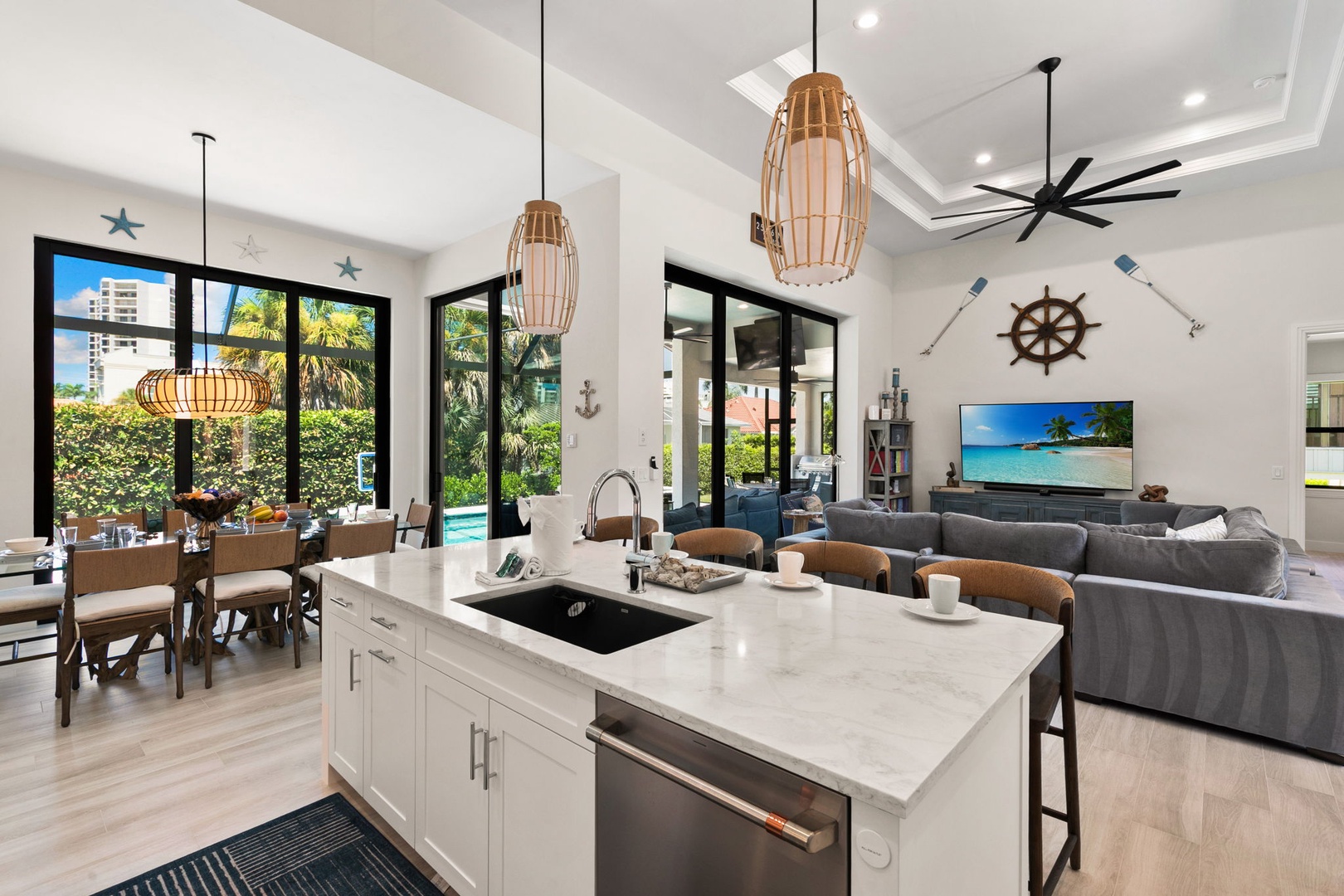 Gather in your spacious open-concept living area, where coastal charm meets modern comfort. Natural light pours through floor-to-ceiling windows, revealing lush tropical views and your private pool just steps away.